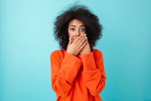 woman wearing orange and covering her mouth